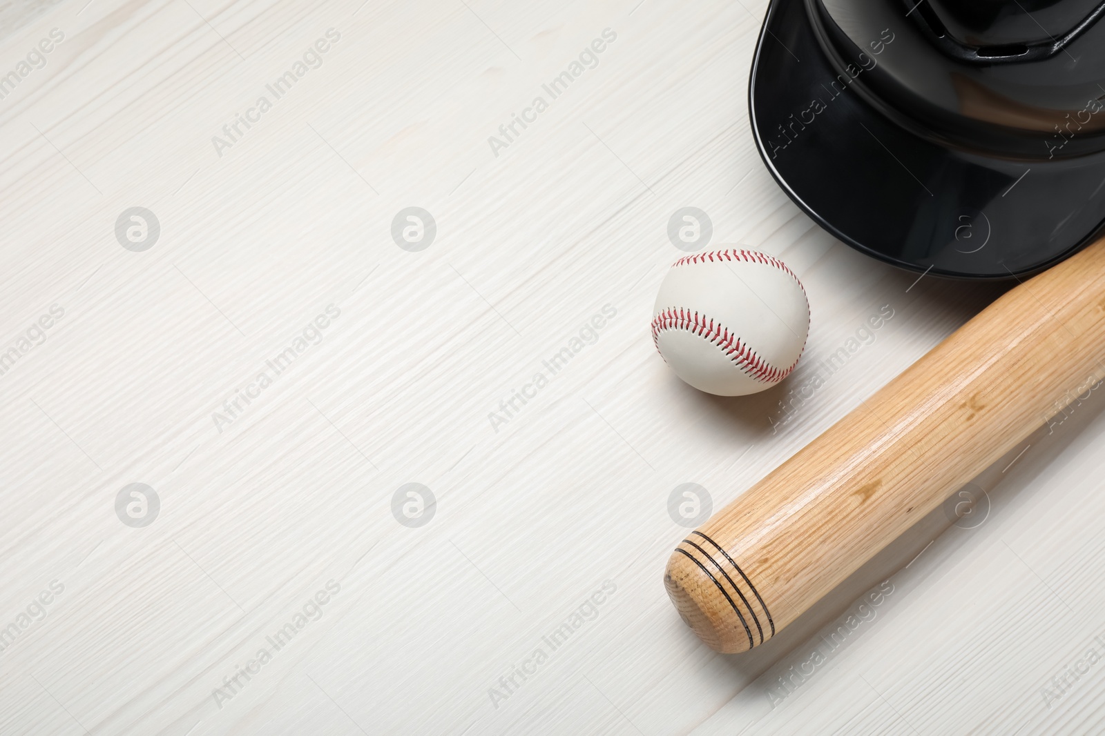 Photo of Sports equipment. Helmet, ball and baseball bat on white wooden table, flat lay. Space for text