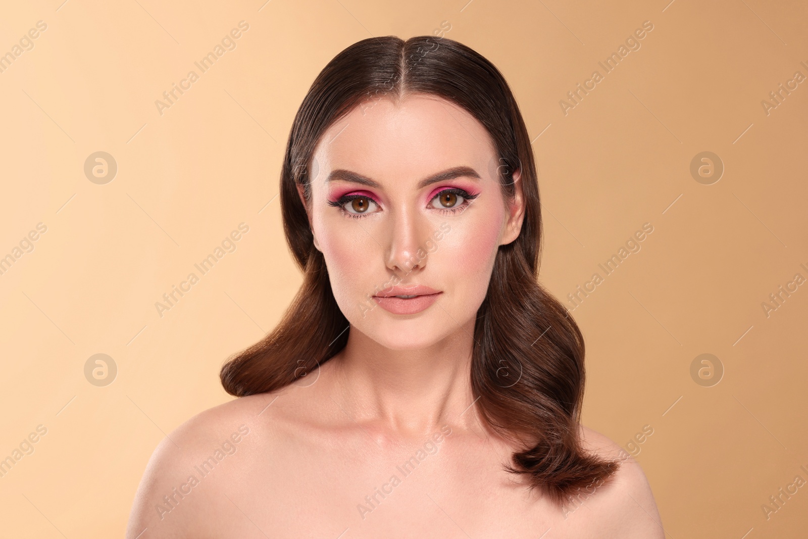 Photo of Portrait of beautiful young woman with makeup and gorgeous hair styling on beige background