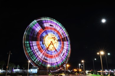 Photo of Beautiful glowing Ferris wheel against dark sky