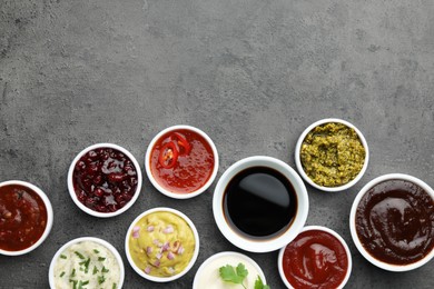 Photo of Different tasty sauces in bowls on grey table, flat lay. Space for text