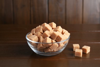 Photo of Brown sugar cubes in glass bowl on wooden table