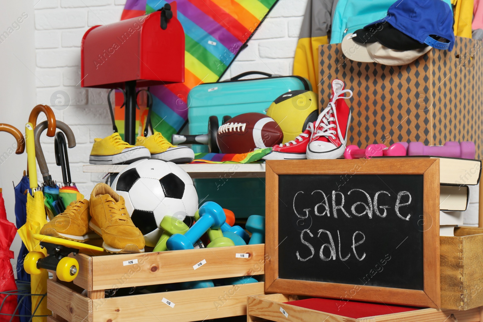 Photo of Sign Garage Sale written on blackboard near many different stuff indoors