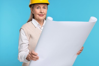 Photo of Architect in hard hat with draft on light blue background