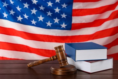 Photo of Judge's gavel and books on wooden table against American flag, space for text