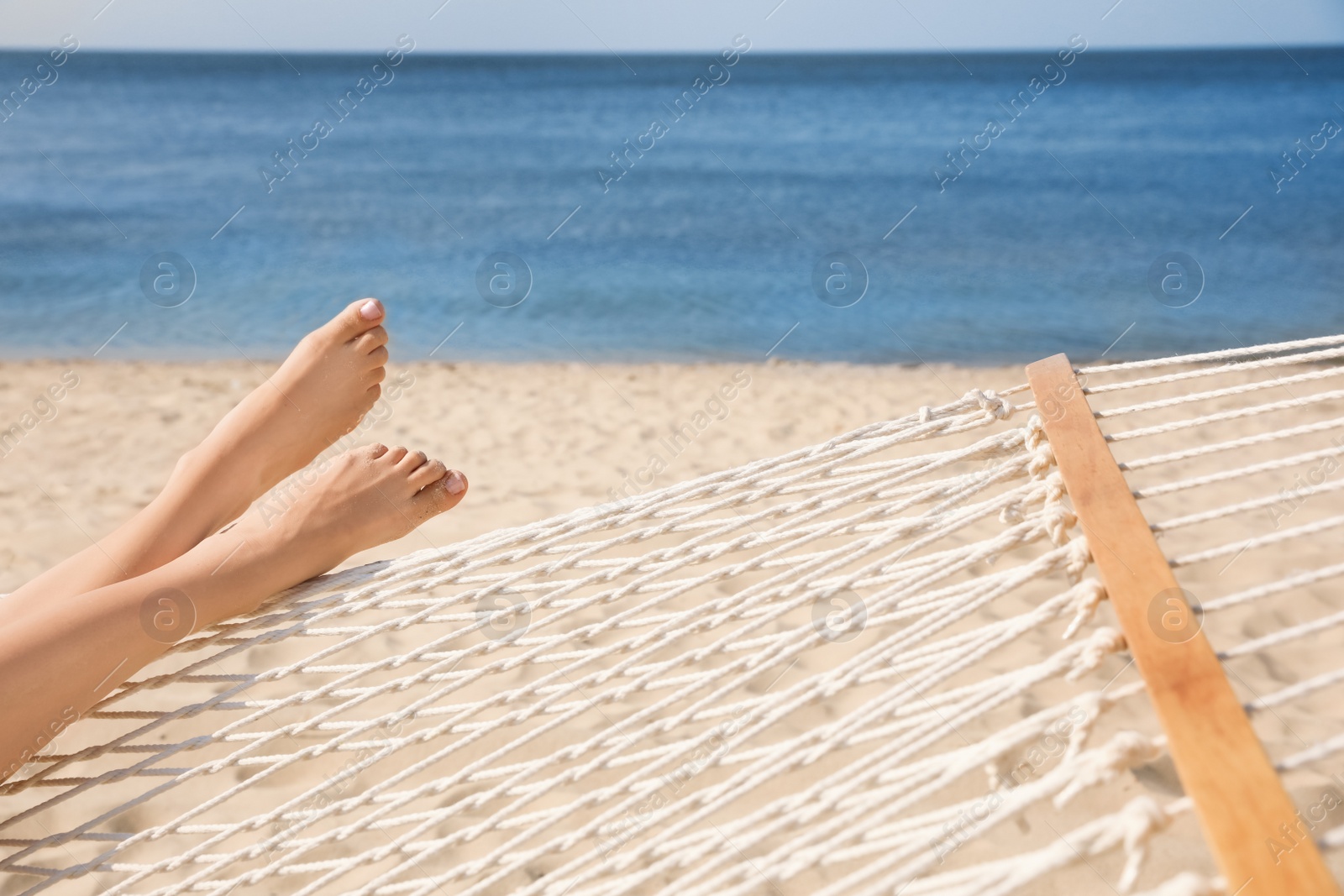 Photo of Young woman relaxing in hammock on beach, closeup