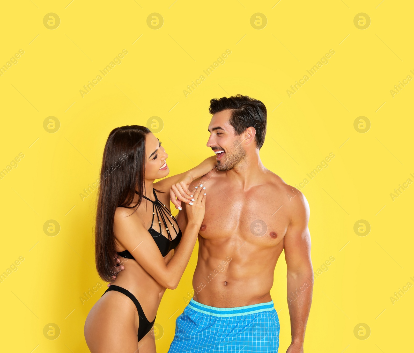 Photo of Young attractive couple in beachwear on yellow background