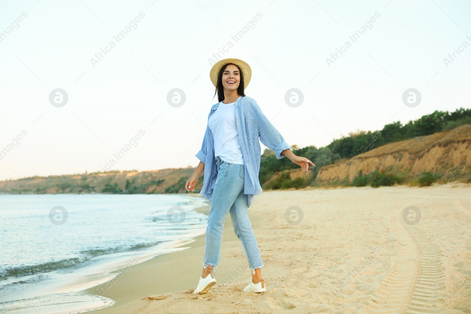 Photo of Beautiful young woman in casual outfit on beach