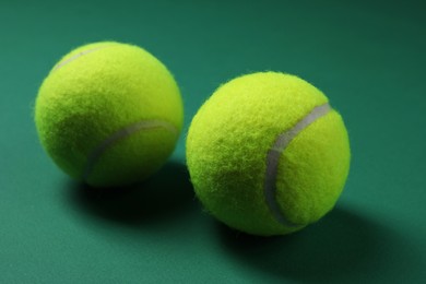 Two tennis balls on green background, closeup