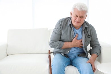 Photo of Senior man having heart attack on sofa