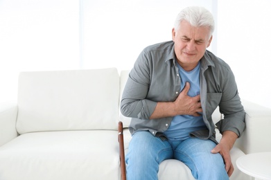 Senior man having heart attack on sofa