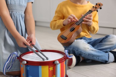 Photo of Little children playing toy musical instruments indoors, closeup