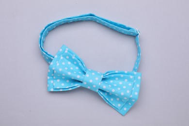 Photo of Stylish light blue bow tie with polka dot pattern on grey background, top view