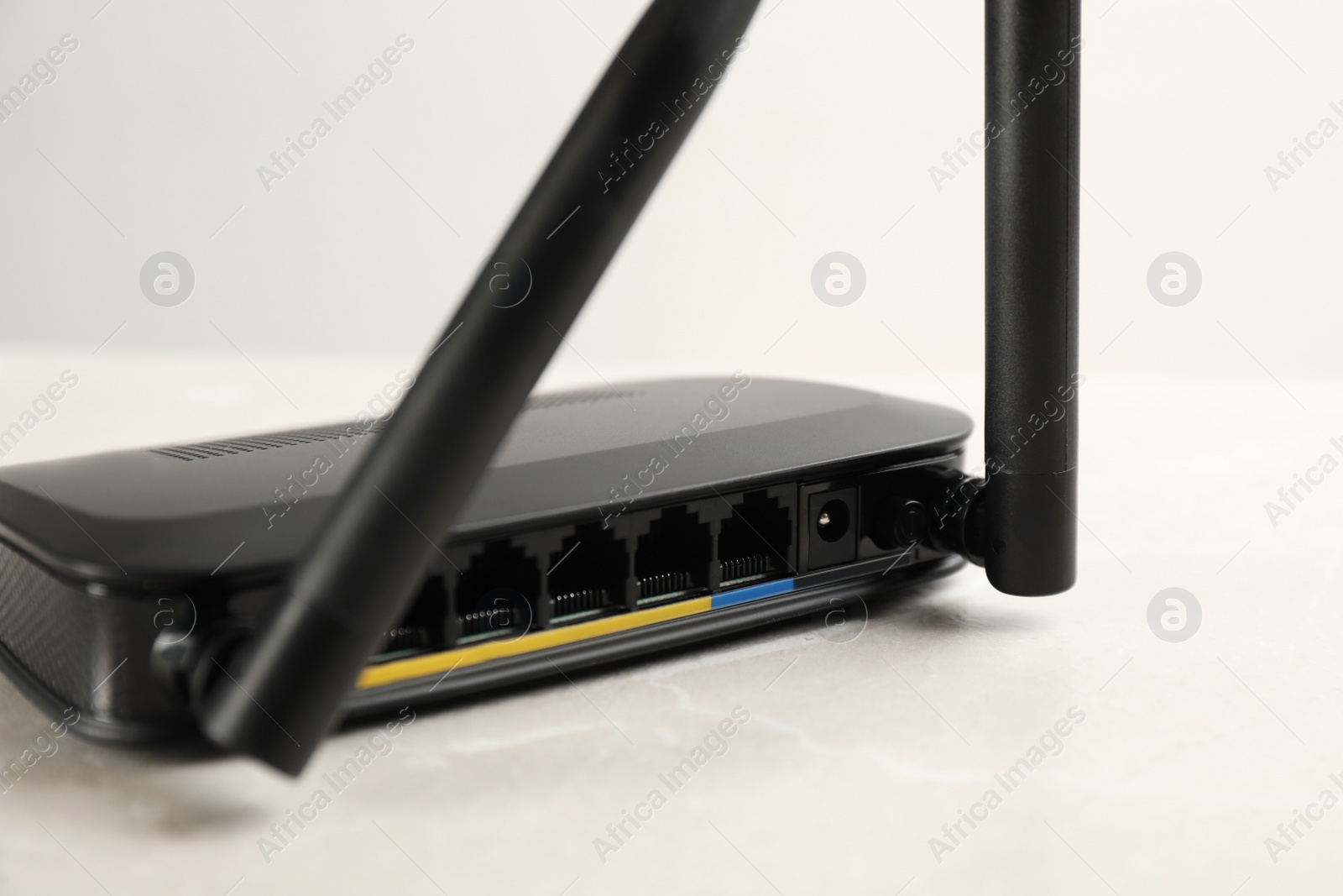 Photo of Modern Wi-Fi router on light grey marble background, closeup