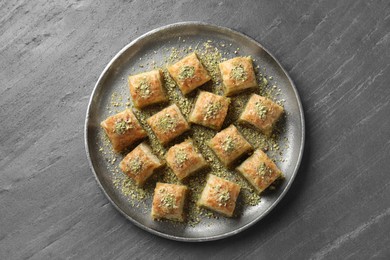 Photo of Delicious fresh baklava with chopped nuts on grey table, top view. Eastern sweets