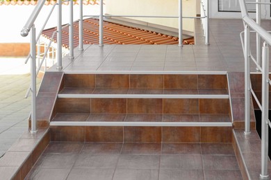 Photo of Beautiful stairs with brown metal railings outdoors