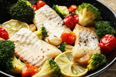 Tasty cod cooked with vegetables in frying pan, closeup