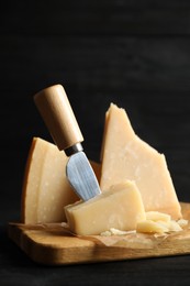 Photo of Pieces of Parmesan cheese and knife on black wooden table
