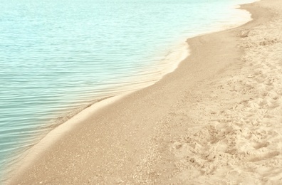 View of sea water and beach sand on sunny summer day