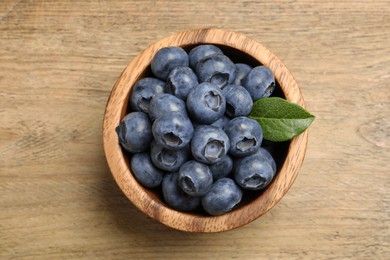 Bowl of fresh tasty blueberries on wooden table, top view