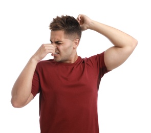 Photo of Young man with sweat stain on his clothes against white background. Using deodorant
