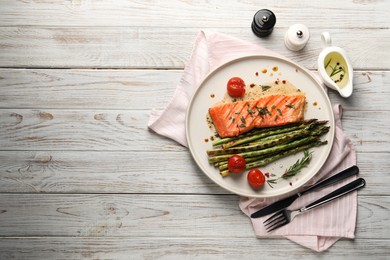 Tasty grilled salmon with tomatoes, asparagus and spices served on wooden table, flat lay. Space for text