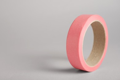 Photo of Roll of pink adhesive tape on grey background. Space for text