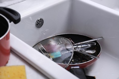 Many different dirty dishes and cutlery in sink