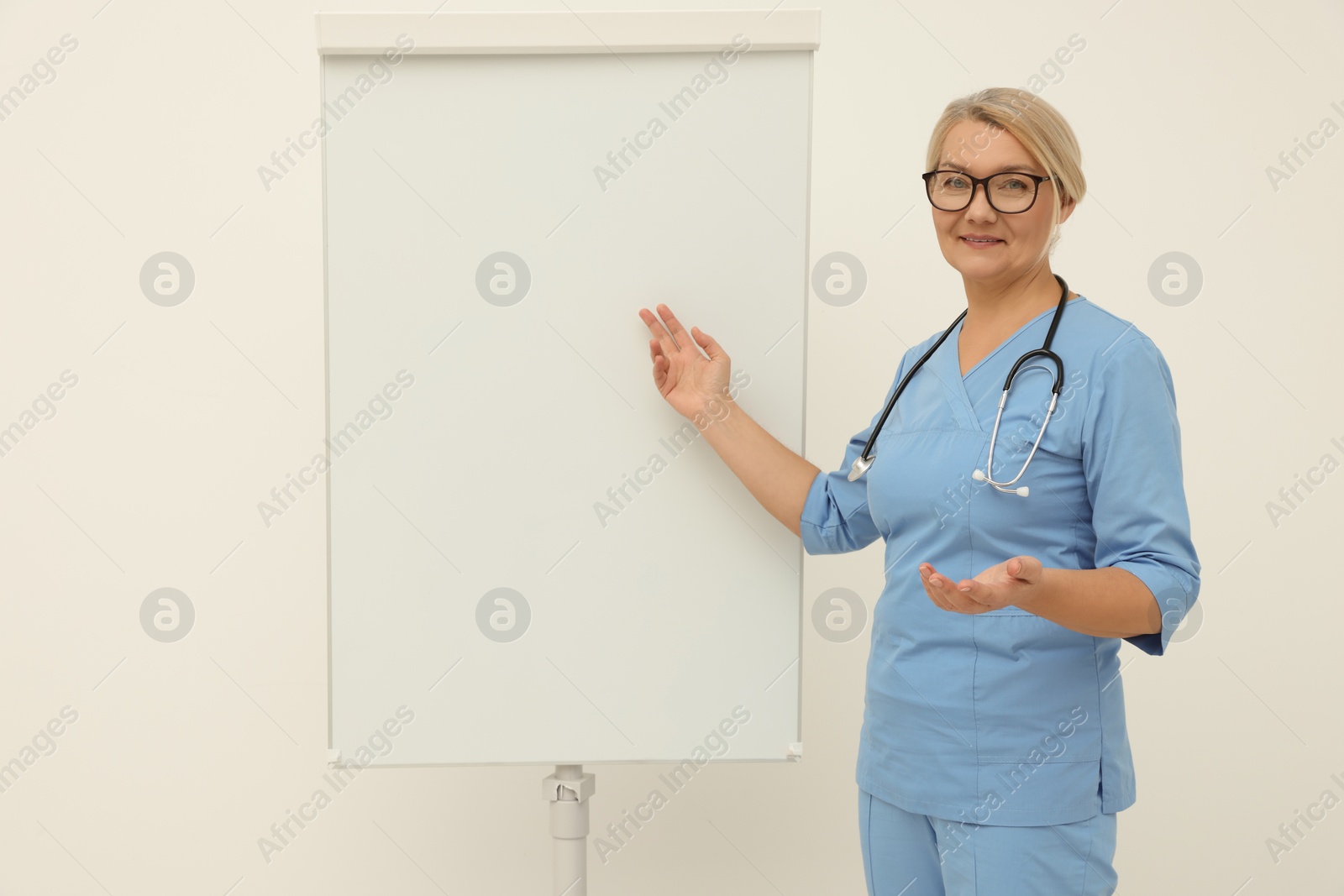 Photo of Professional doctor explaining something near flipchart indoors