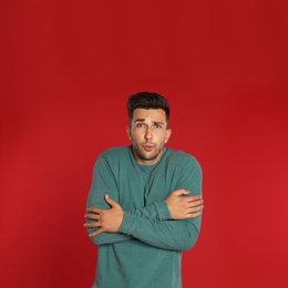 Photo of Young man in sweatshirt on red background. Winter season