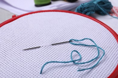Photo of Embroidery hoop with fabric and needle, closeup