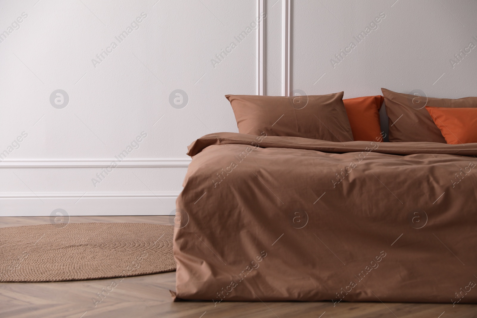 Photo of Bed with orange and brown linens in stylish room