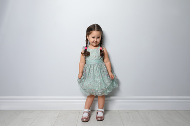 Cute little girl near light grey wall