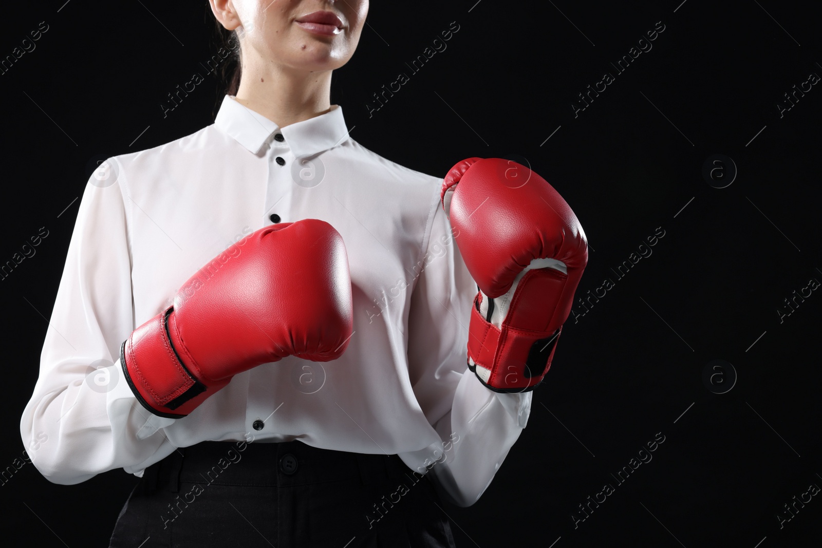 Photo of Businesswoman in shirt wearing boxing gloves on black background, closeup. Space for text