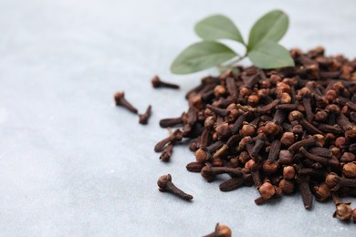 Photo of Pile of aromatic dried clove buds and leaves on grey table, closeup. Space for text