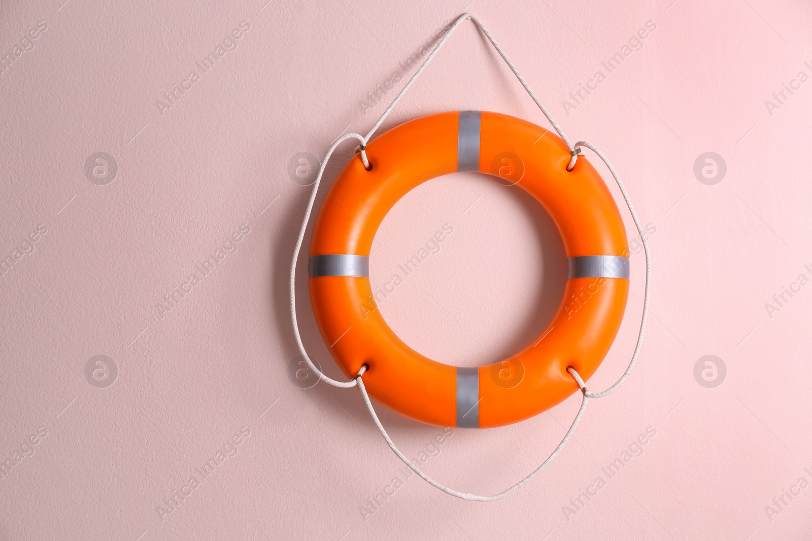 Photo of Orange lifebuoy on pink background. Rescue equipment