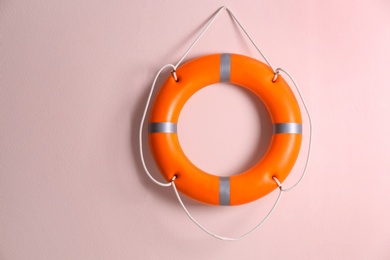 Photo of Orange lifebuoy on pink background. Rescue equipment