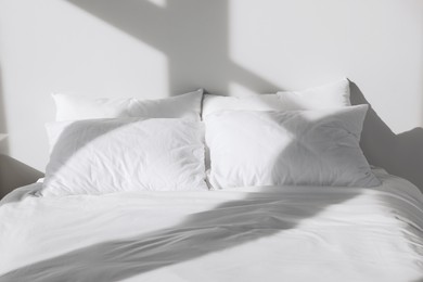 Photo of White soft pillows on bed in room