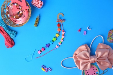 Photo of Handmade jewelry kit for kids. Colorful beads, bow, and bracelets on light blue background, flat lay