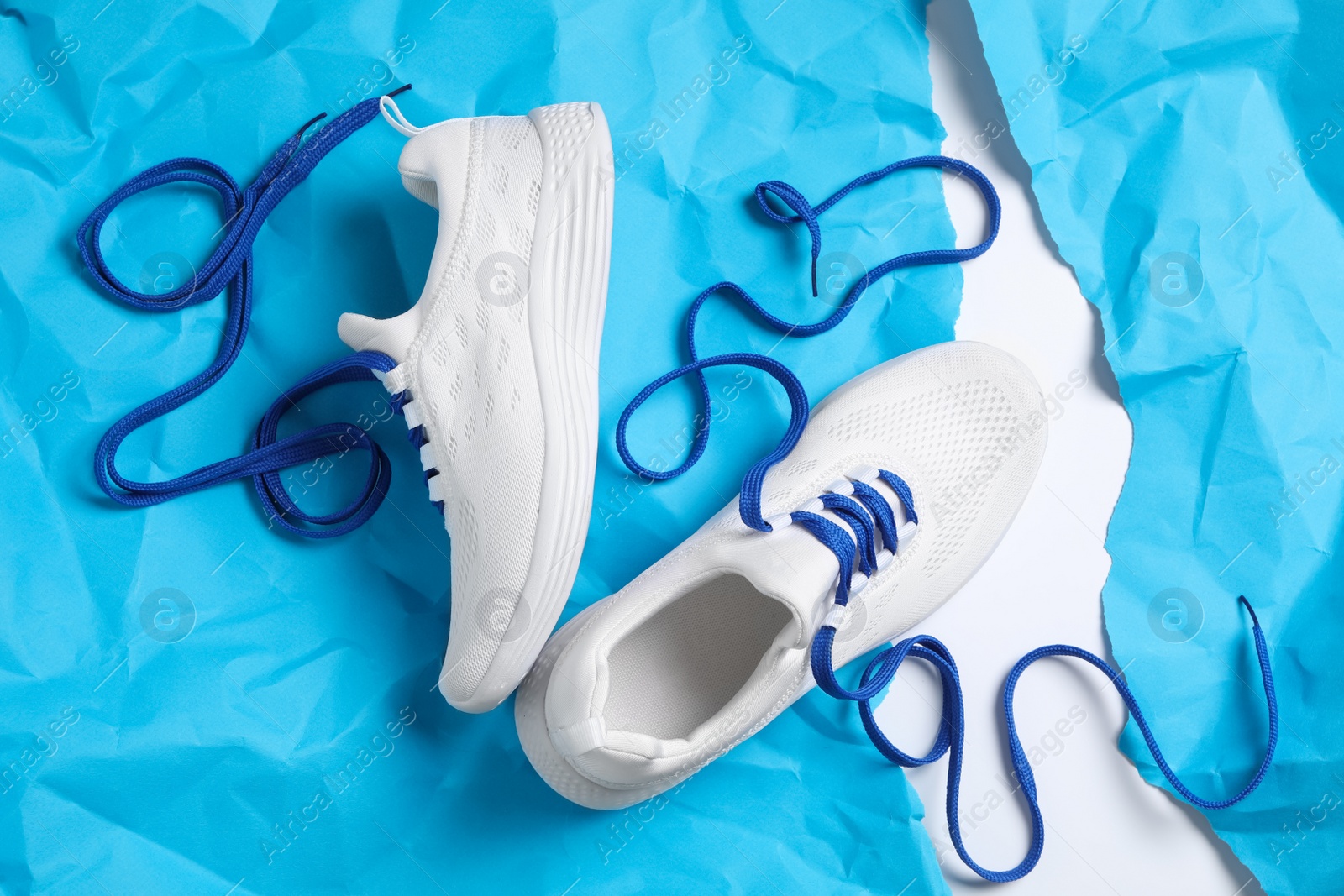 Photo of Pair of stylish shoes with laces on light blue paper, flat lay