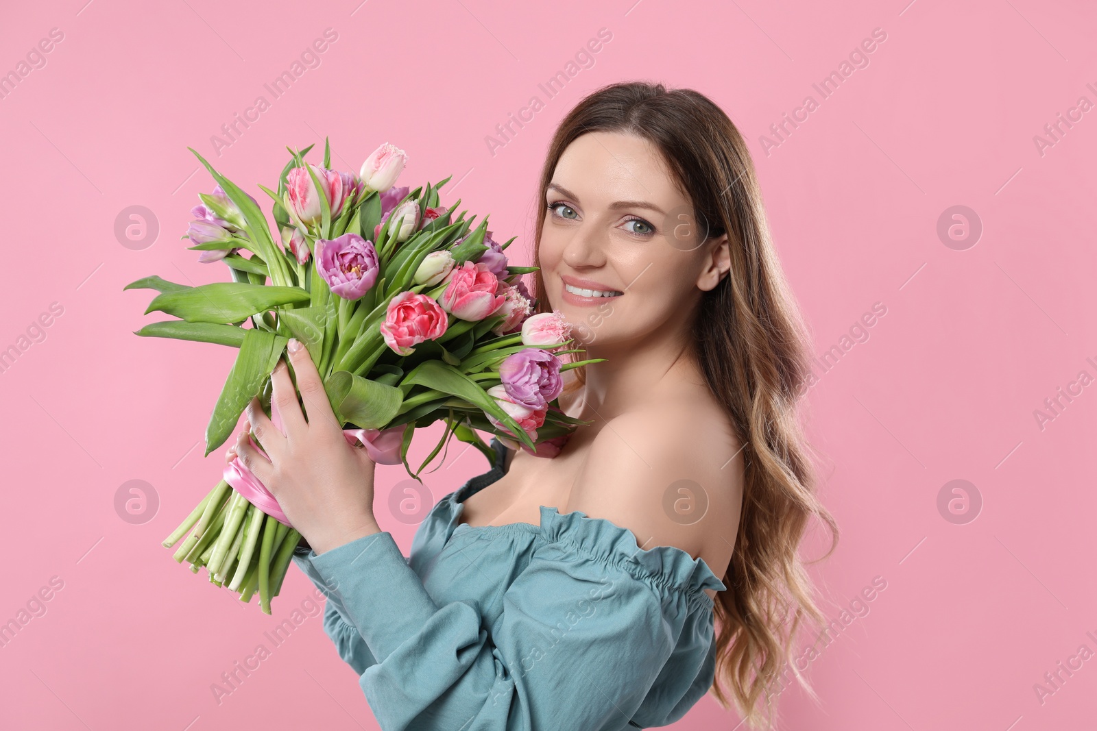 Photo of Happy young woman with bouquet of beautiful tulips on pink background