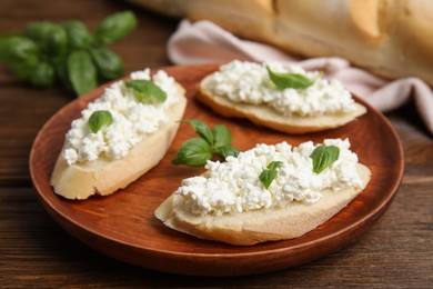 Bread with cottage cheese and basil on wooden table, closeup