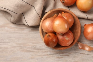 Many ripe onions on wooden table, flat lay. Space for text