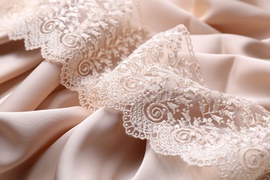 Photo of Beautiful lace on beige fabric, closeup view