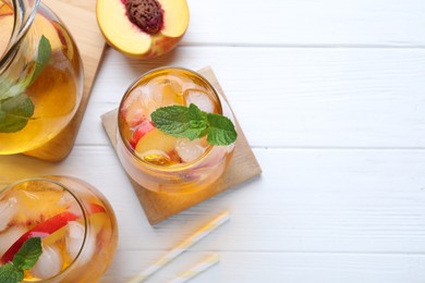 Photo of Delicious peach lemonade made with soda water on white wooden table, flat lay. Space for text