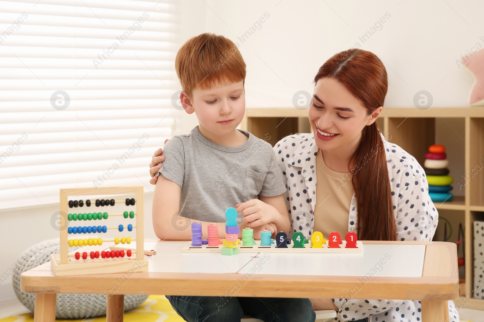 Photo of Happy mother and son playing with Educational game Fishing for Numbers at desk in room. Learning mathematics with fun