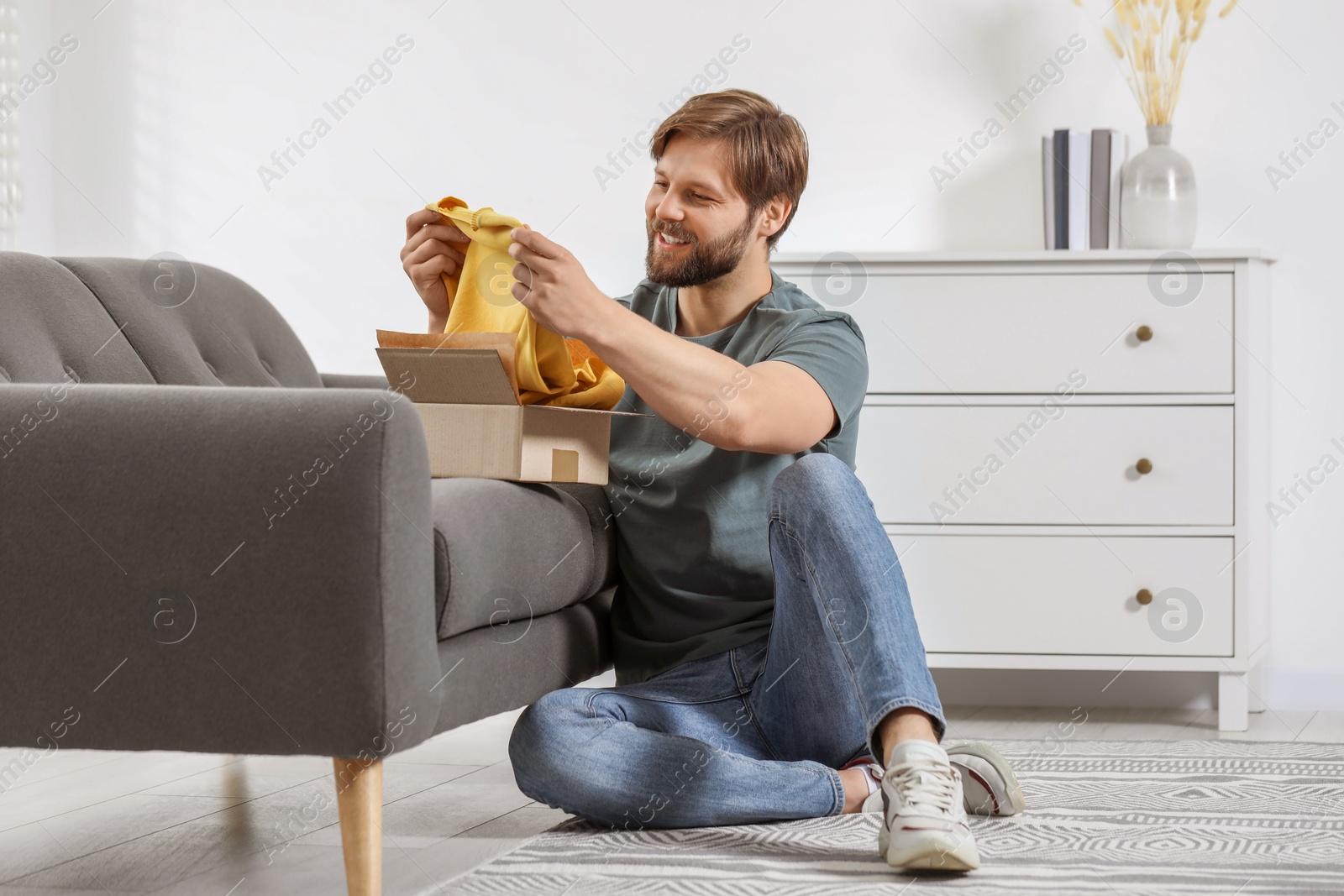 Photo of Happy man with parcel at home. Internet shopping