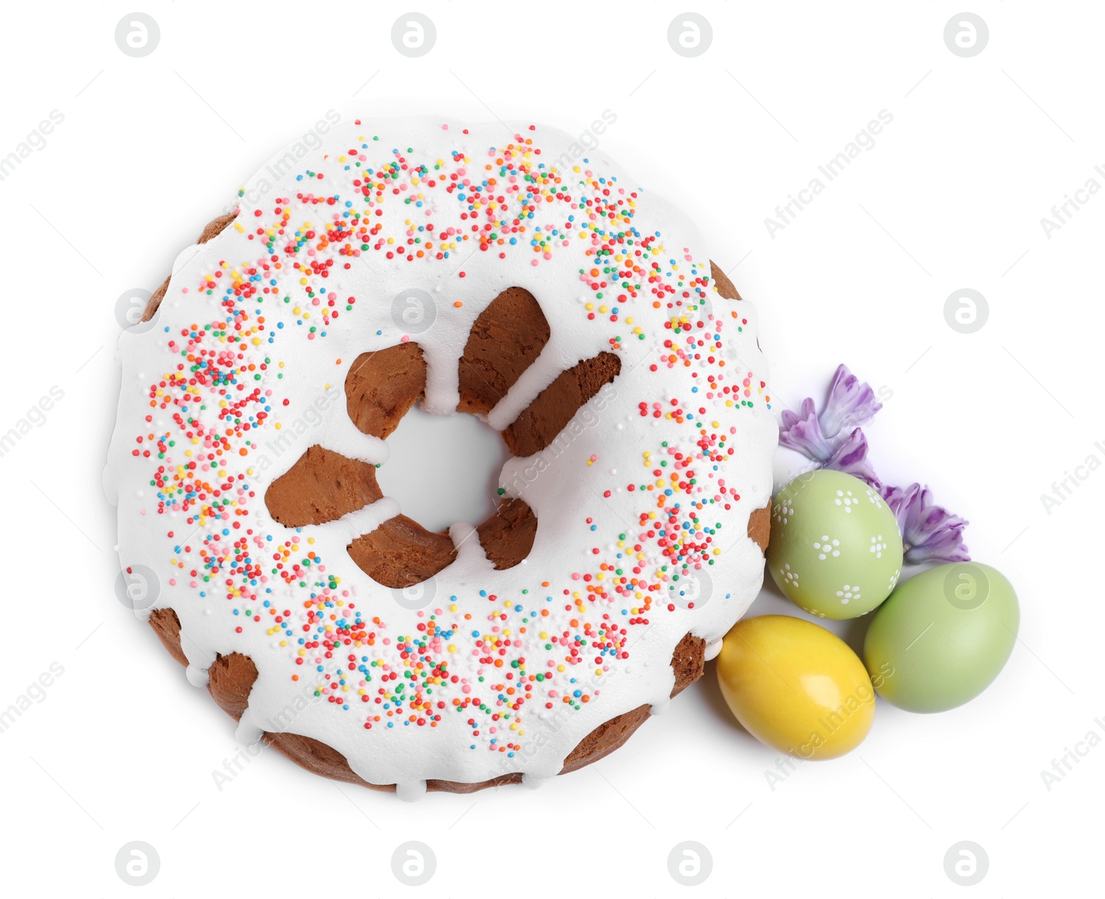 Photo of Glazed Easter cake with sprinkles, painted eggs and flowers on white background, top view