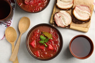 Stylish brown clay bowl with Ukrainian borsch served on white tablecloth, flat lay