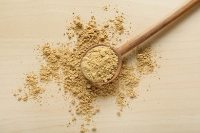 Photo of Spoon with aromatic mustard powder on wooden table, top view