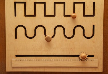 Wooden sliding maze with different lines on table. Montessori toy